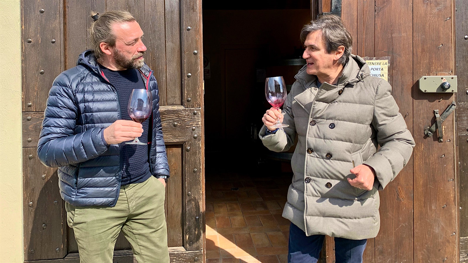 Giovanni Bigot and Giuseppe Caviola standing and talking with glasses of wine in hand